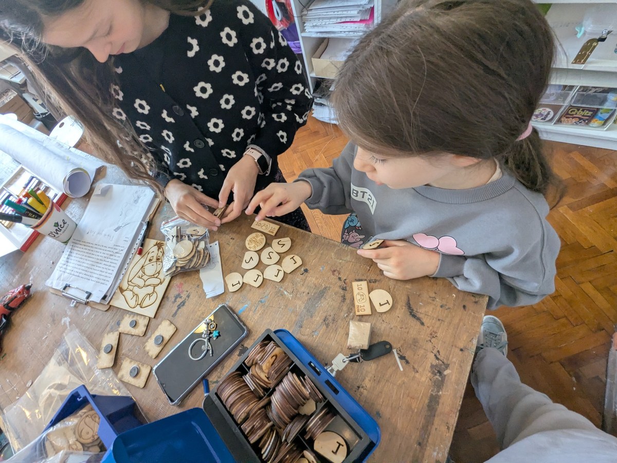 Older and younger players using fish coins and game pieces together in a practical market moment.